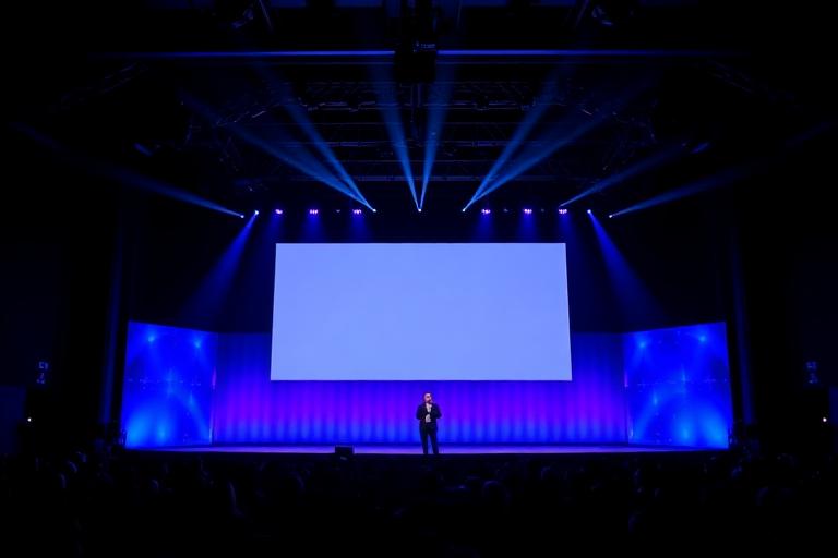 Speaker on a large stage at an AlwayzON regional Summit